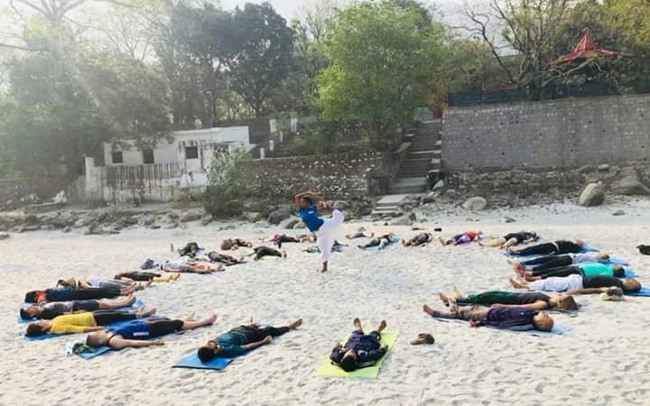 Yoga students in savasana on the banks of the Ganges during a Deep Yoga retreat in Rishikesh